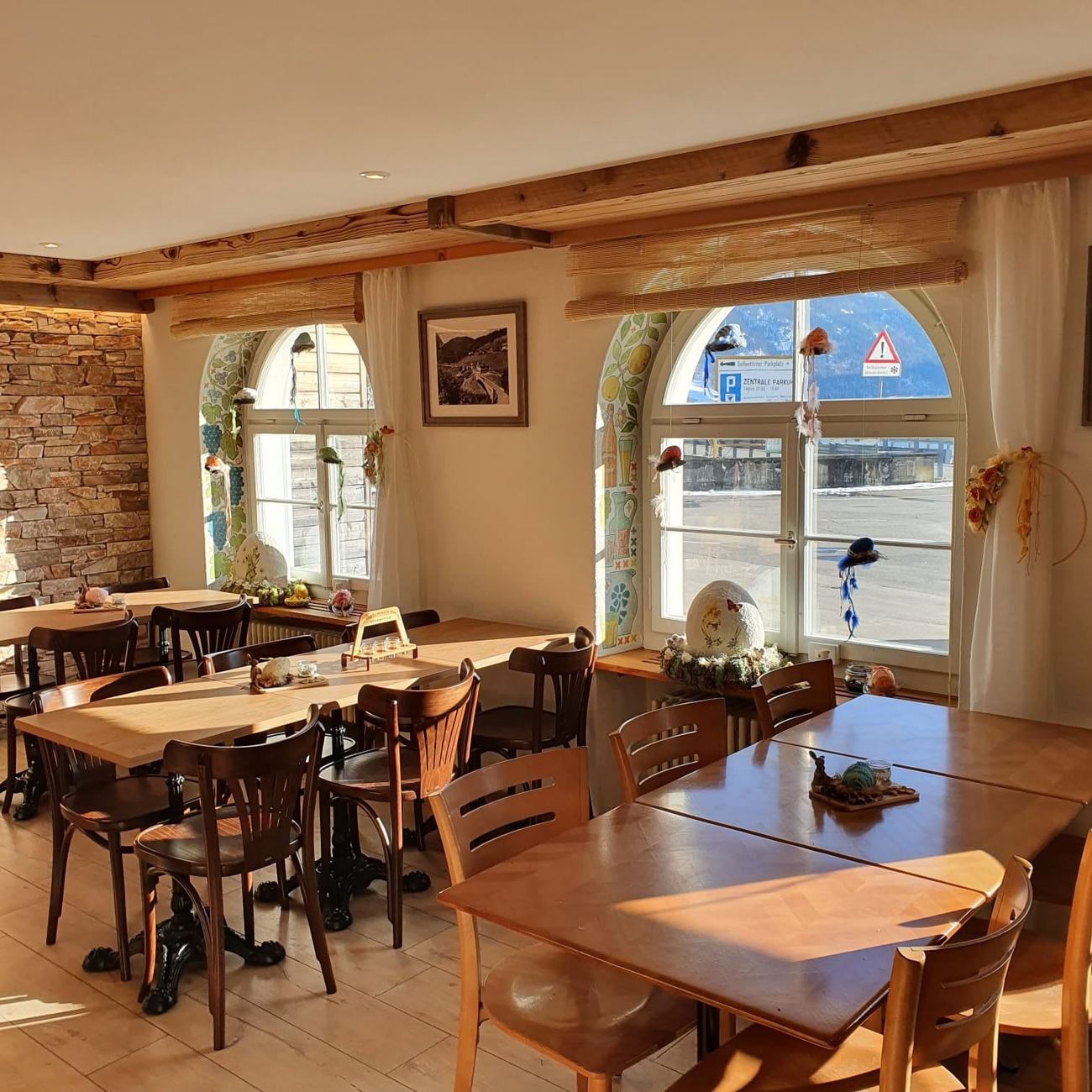 Bistro am See mit Holztischen und Rundbogenfenstern im Sonnenlicht